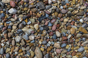 Pebble beach background, small wet colored stones on a sea shore