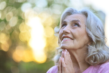 Close up portrait of cute senior woman praying outdoors