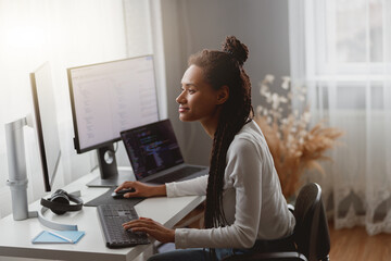 Side view of mixed-race young professional concentrated skilled web expert working on computer