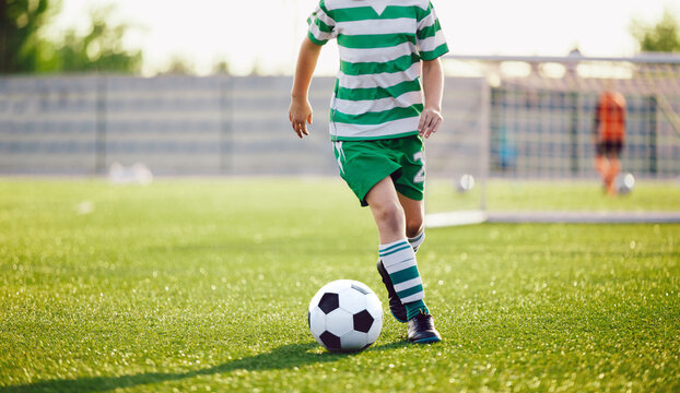 Football Player Running Ball Background. Low Angle Image of Soccer Boy Kicking Ball on Grass Training Field. School Boy in Striped Soccer Jersey Shirt