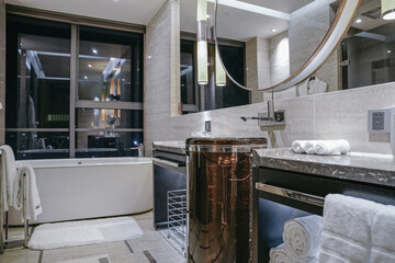 modern bathroom has a round mirror, a large bath and a white towel