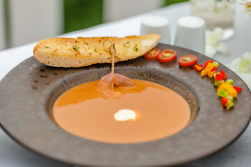Fine dining - lobster soup at luxury restaurant. A plate of pureed seafood soup is decorated with colorful vegetables and a piece of grilled bread. Beautiful serving of the dish in a restaurant