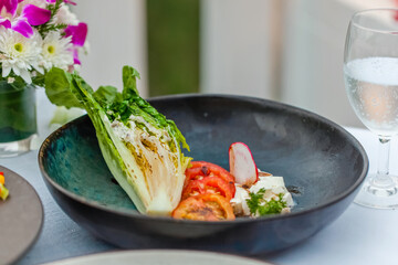Lunch at an expensive restaurant. Set table with delicious dishes and decorations. Plate with grilled cheese and vegetables. Fine dining luxury restaurant