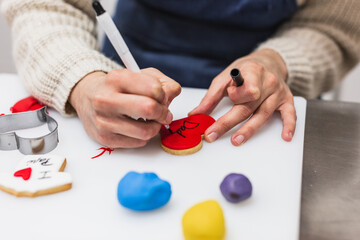 Close-up view of pastry chef writing about decoration of cookie