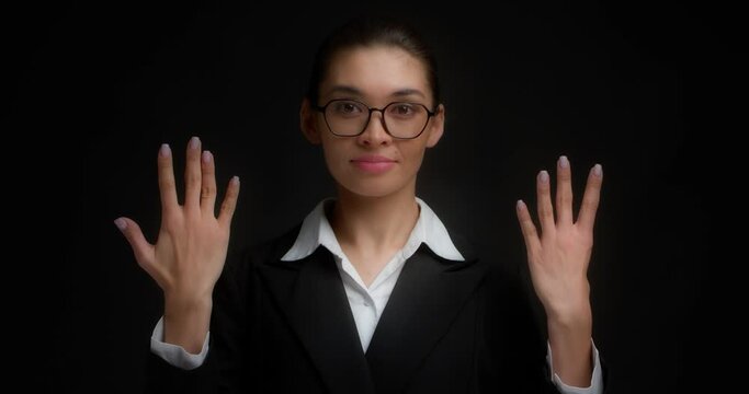 Business woman with glasses in business clothes with a serious face shows nine finger with her right hand. Isolated on a black background.