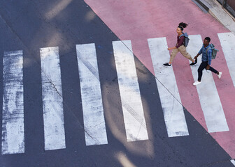 Two young pedestrians cross the road on a crosswalk in the city