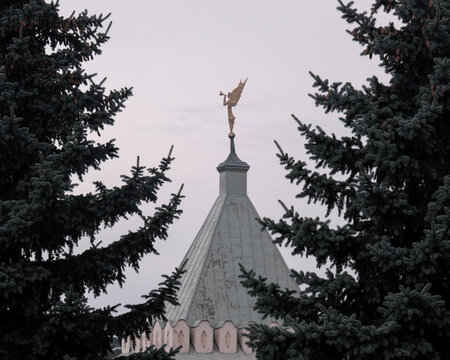 View of Angel on the top of Gate tower of Optina Pustyn monastery on cloudy summer day. Kaluga Oblast, Russia.