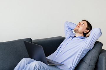 Fototapeta premium Young man resting on a couch with a laptop