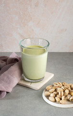 Pistachio milk in a glass on the table, on a light background. This milk is an excellent source of antioxidants, and heart-healthy fats. Vegetarian food, healthy food