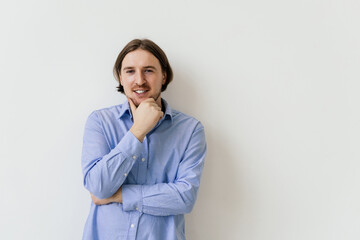 Getting idea. Smiling thoughtful handsome man standing on white isolated background and touching his chin with hand