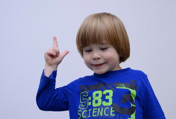 Cute european boy, blond hair holds index finger up. portrait isolated white background Space for text