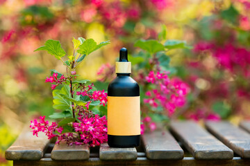 Cosmetic bottle on wooden table in blooming tree spring garden