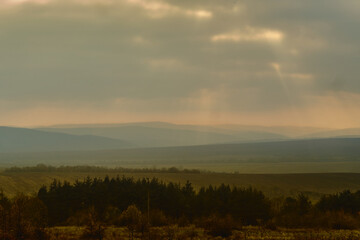 A landscape of countryside with a meadow and mountains on the horizon. 