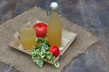 Naturtrüber Apfelsaft in einer Flasche und einem Glas dekoriert auf einem Serviertablett mit...