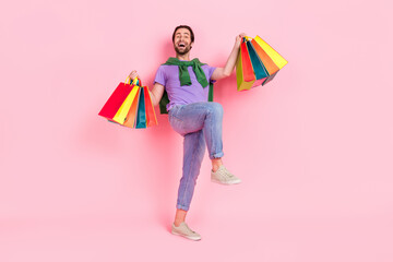 Full body photo of ecstatic overjoyed male have fun go shopping visit mall center isolated on pink color background