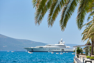 Palm leaves on the background of the sea and luxury yacht