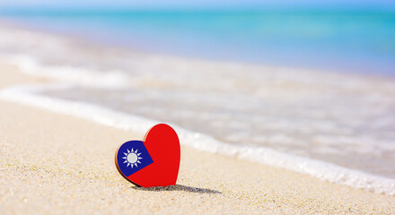Flag of the Taiwan in the shape of a heart on a sandy beach. The concept of the best vacation in Taiwan resorts