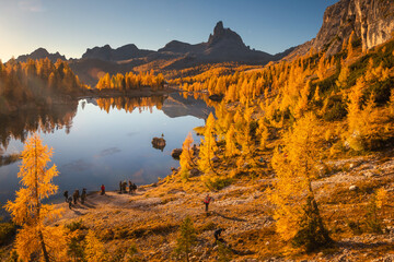 Fototapeta na wymiar Fall sunrise on Lake Federa in the Italian Dolomites. Yellow larches create a unique atmosphere of this place.