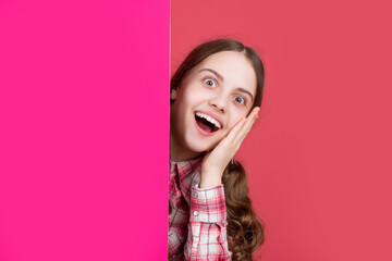 shocked girl behind blank pink paper with copy space for advertisement