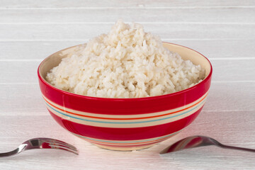 Cooked white rice in red ceramic bowl.