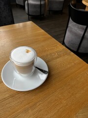 Glass of cappuccino on wooden table in a cafe