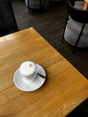 Glass of cappuccino on wooden table in a cafe