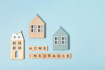 Home insurance message and wooden house over blue background. House insurance concept, residential home real estate protection. Top view, flatlay