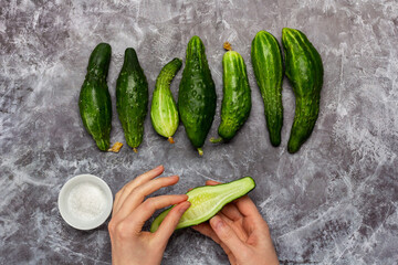 sprinkle with salt half of fresh ugly cucumber  on dark concrete background