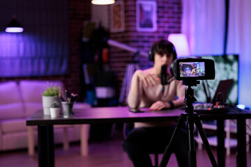 Caucasian woman recording online podcast discussion on camera, vlogging live channel content....