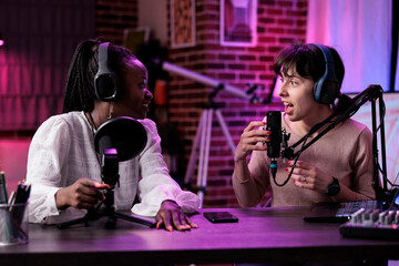 Multiethnic team of women hosting podcast conversation in studio, filming online vlog and chatting...