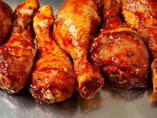 Raw chicken drumsticks on a metal tray. Poultry product for barbeque. Summer season food.