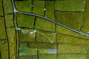 Green grass fields between stone fences of walls. Aerial top down view on meadow. Irish landscape. Aran Island, county Galway, Ireland. Popular and famous travel area. - obrazy, fototapety, plakaty