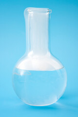 Science laboratory, scientific experiment and lab test concept with dry ice in a glass chemistry beaker isolated on blue background
