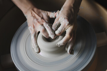 Hands working with clay on potter's wheel, craftsmanship, traditional craft making, pottery