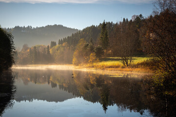 Misty and foggy autumnal morning by the calm lake