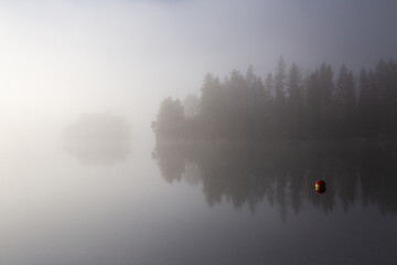 Misty and foggy autumnal morning by the calm lake