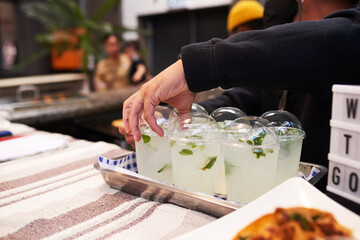 A man arranges a tray of fresh lemonade at a taco stall
