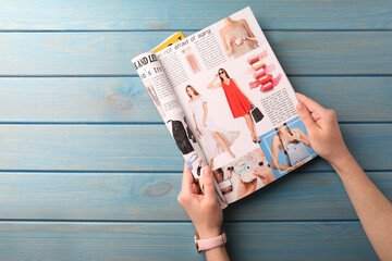 Woman reading magazine at light blue wooden table, top view. Space for text