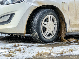 dirty snow on a car wheel in the wheel arch 