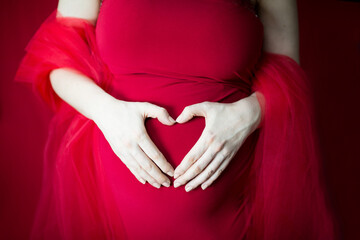 9 miesięcy ciąży, kobieta i mężczyzna trzymają ręce w kształcie serca na brzuchu ciążowym - obrazy, fototapety, plakaty