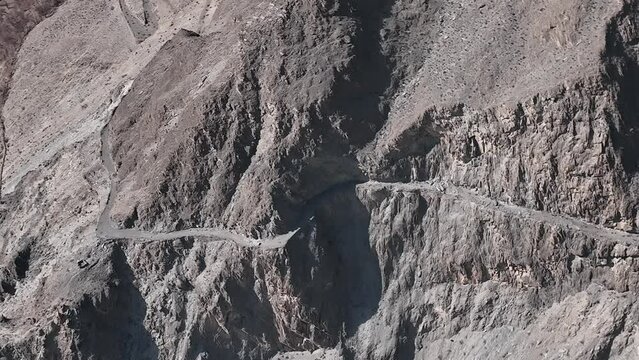 Pakistani trucks travel on dangerous paved road along the mountain, transport goods via Karakoram highway. Gilgit Baltistan, Pakistan.