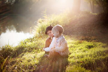 Dzieci bawią się w parku i siedzą na trawie w promieniach zachodzącego słońca