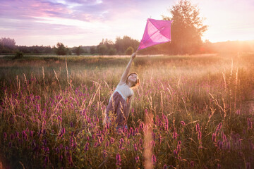 Dziewczynka biega z latawcem po łące pełnej kwiatów, Zachodzące słońce i zabawa dzieci