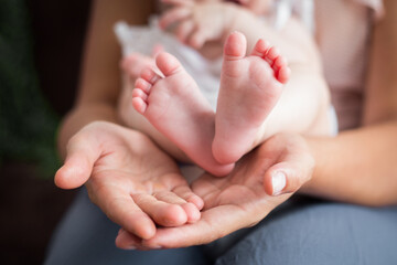 Fototapeta Rodzice trzymają w rękach swoje malutkie dziecko, stopy i rączki dziecka w dłoniach rodziców obraz