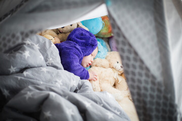 Dziecko śpi w namiocie tippi w towarzystwie swoich przytulanek, popołudniowa drzemka małego chłopca - obrazy, fototapety, plakaty
