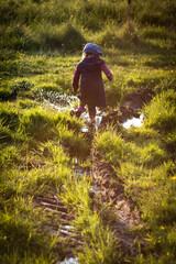 Dziecko bawi się w kałuży w letnich promieniach słońca © Katarzyna Krociel