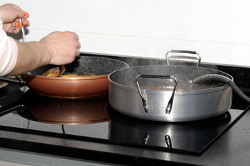 The arms and hands of a woman cooking in her home kitchen. Photograph with space for copy space. Selective focus