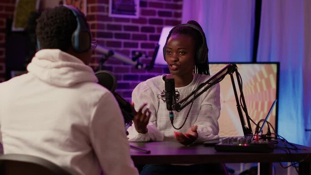 Closeup Of African American Podcast Host Interviewing Male Influencer For Online Broadcast Using Professional Microphones And Audio Mixer. Woman Having Conversation With Social Media Vlogger.