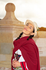 Fototapeta premium Woman in traditional peasant dress posing in front of colonial architecture