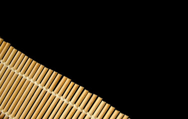 Bamboo sticks. Bamboo roller mat for cooking sushi on black background. Copy space for text.